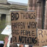 protest sign says "bad things happen when good people do nothing"